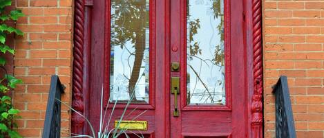 Una puerta roja con una pequeña planta en maceta en el escalón.