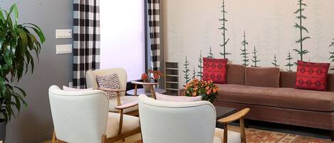 A modern living room with a sofa, two armchairs, a coffee table, and a chandelier.