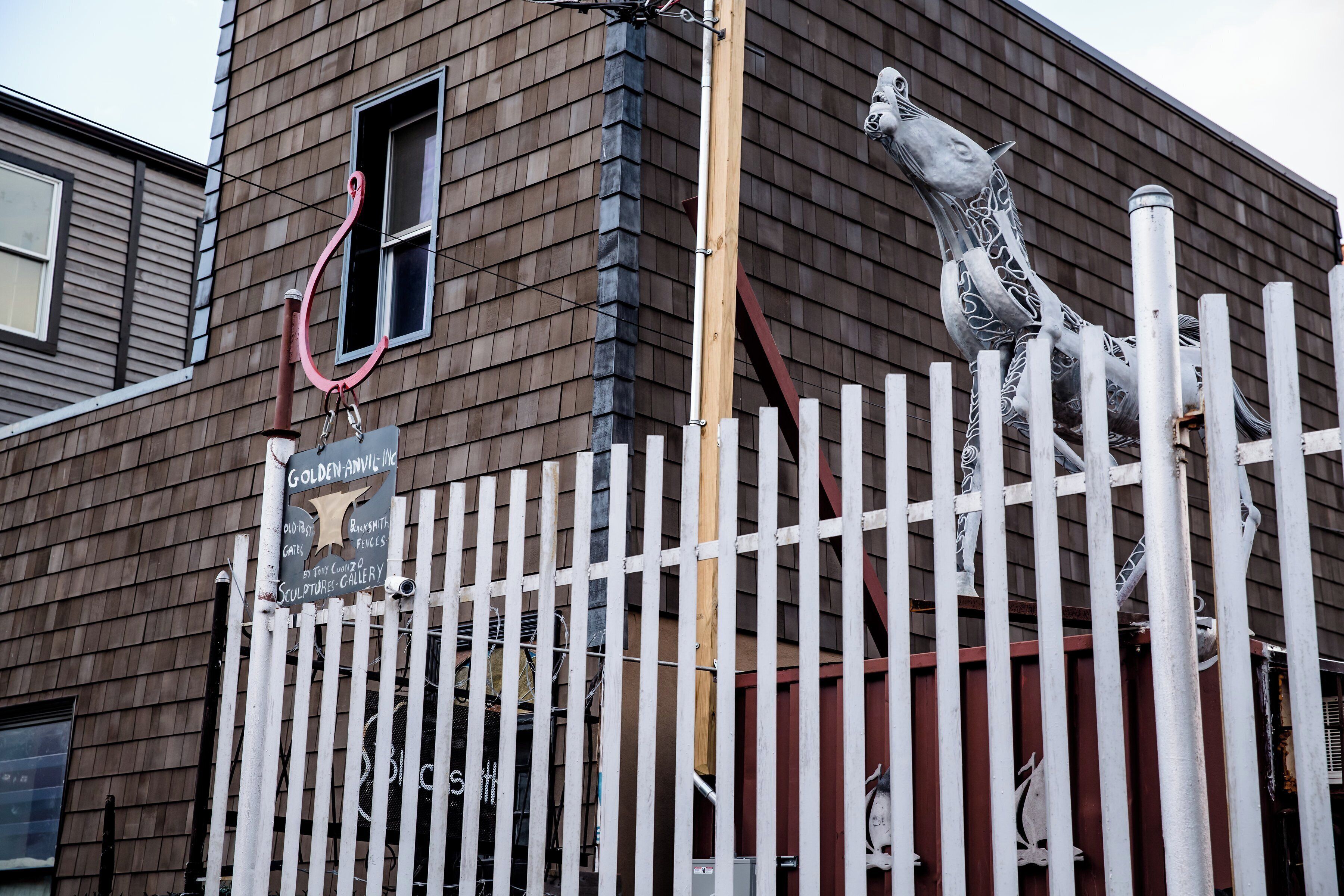 A building with a wooden exterior, a white fence, and a sculpture of a giraffe.