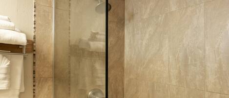 A bathroom with a glass-enclosed shower, a toilet, and a towel rack.