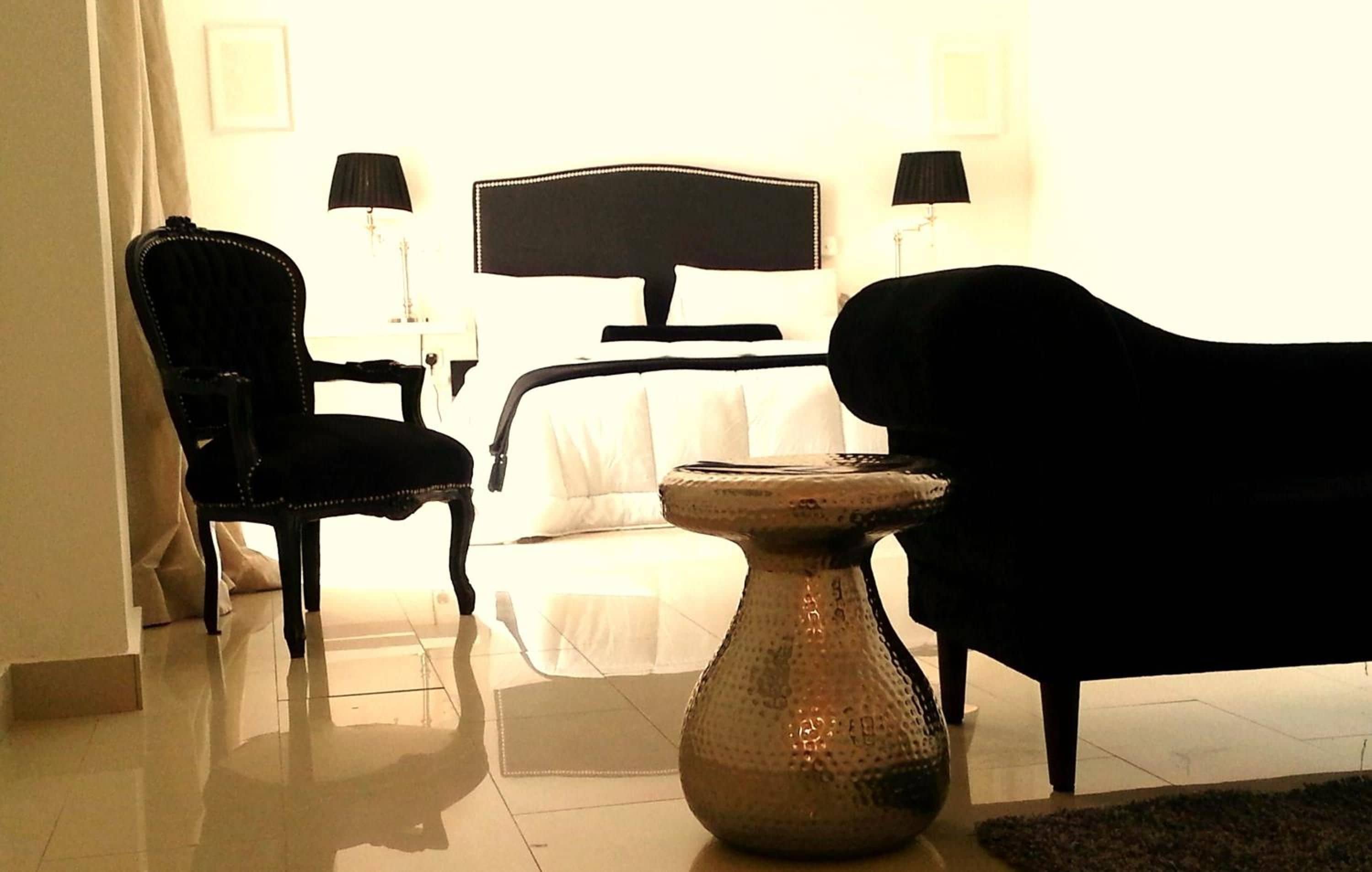 A hotel room with a bed, a chair, a table, and two lamps.