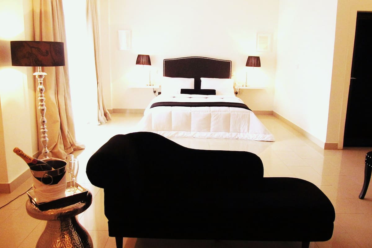 A hotel room with a bed, two bedside lamps, a chair, and a decorative vase.