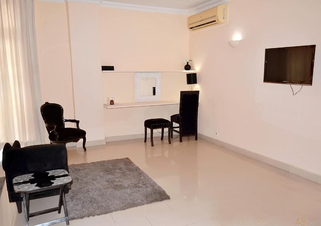 Un salon comprenant un téléviseur à écran plat, un canapé, un fauteuil, une petite table et un tapis.