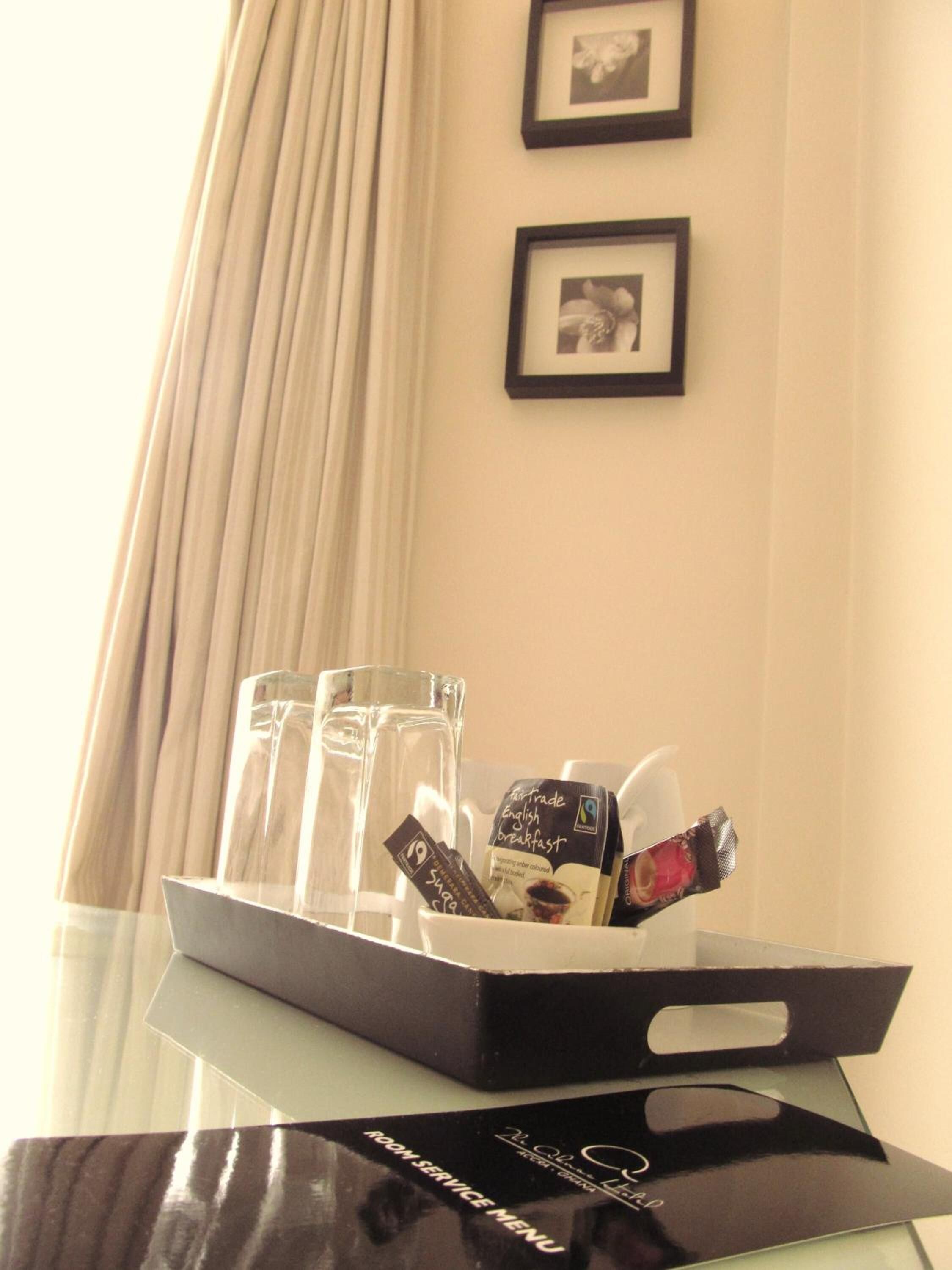 A tray with a black bag labeled "ROOM SERVICE MENU" and a box of "Fairtrade English Breakfast" coffee.