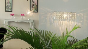 A room with a white console table, two framed artworks, a chandelier, and a wall sign reading "The Velvet Lounge". - The Aknac Hotel (Accra)