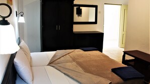 A bedroom with a bed, a wardrobe, a mirror, and a bedside table. - Badala Park Hotel (Serrekunda)