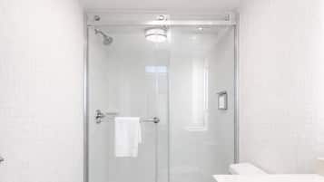 A modern bathroom with a glass-enclosed shower, a white toilet, and a wooden vanity.