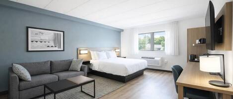 Habitación de hotel con cama, sofá, escritorio y televisor.