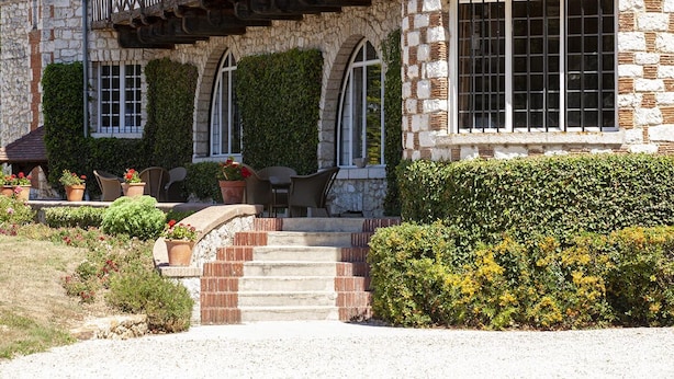 A stone building with a balcony, steps leading to a door, and potted plants. - Chambres d'Hôtes Le Manoir de Beaumarchais (Les Chapelles-Bourbon)