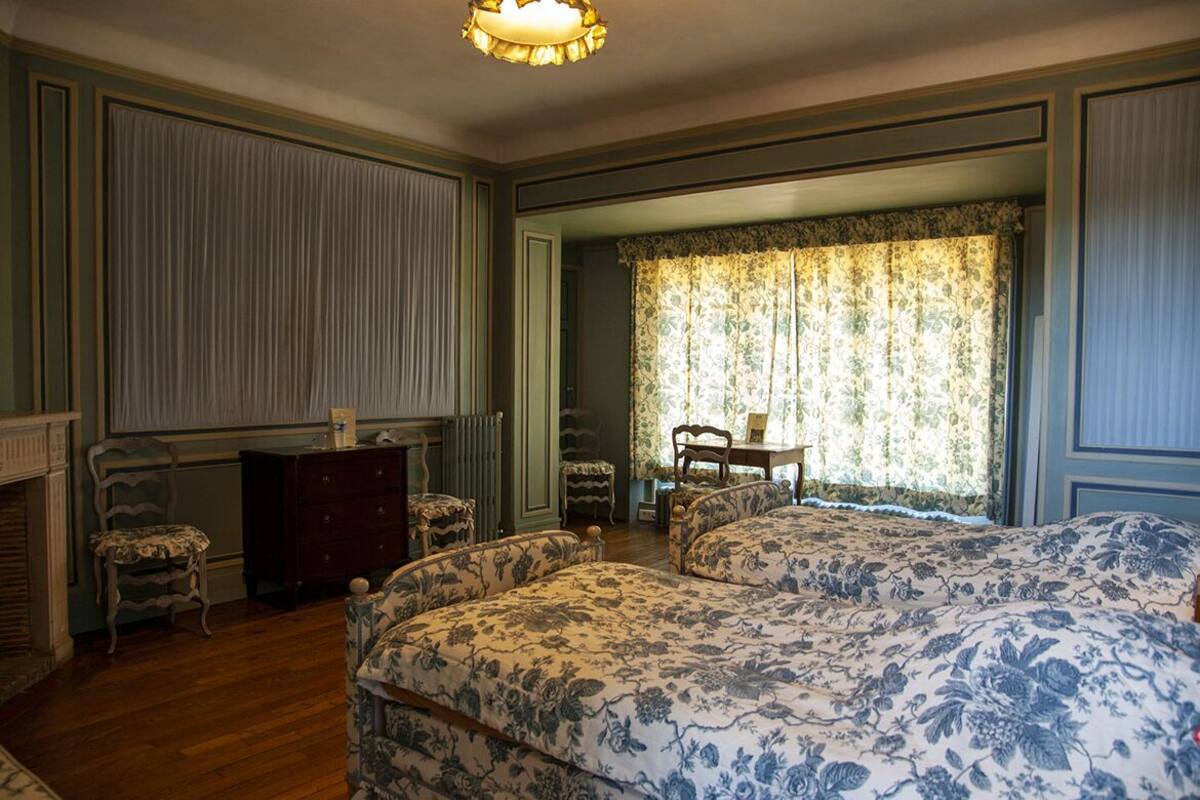 Une chambre avec deux lits, une commode, une chaise et une table.