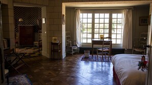 A room with a large window, a bed, a desk, and a chair. - Chambres d'Hôtes Le Manoir de Beaumarchais (Les Chapelles-Bourbon)