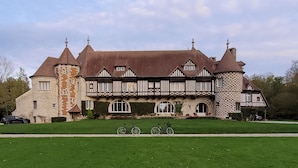 A large, historic building with a stone tower, multiple chimneys, and a symmetrical facade with timber framing. - Chambres d'Hôtes Le Manoir de Beaumarchais (Les Chapelles-Bourbon)