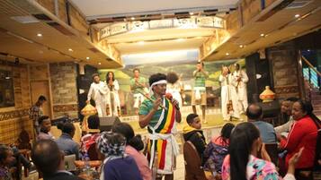 A group of people in a restaurant with a stage and a mural in the background.