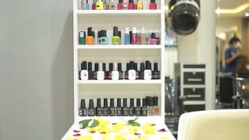 Un salón con una estantería blanca llena de frascos de esmalte de uñas de diferentes colores.