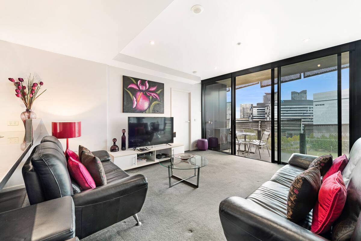 A modern living room with a sofa, coffee table, TV, and artwork.