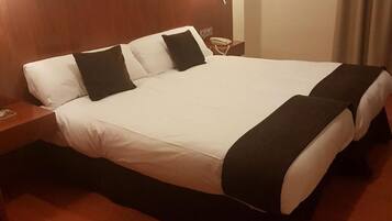 Una habitación de hotel con una cama grande, una mesita de noche, una lámpara y una obra de arte en la pared.