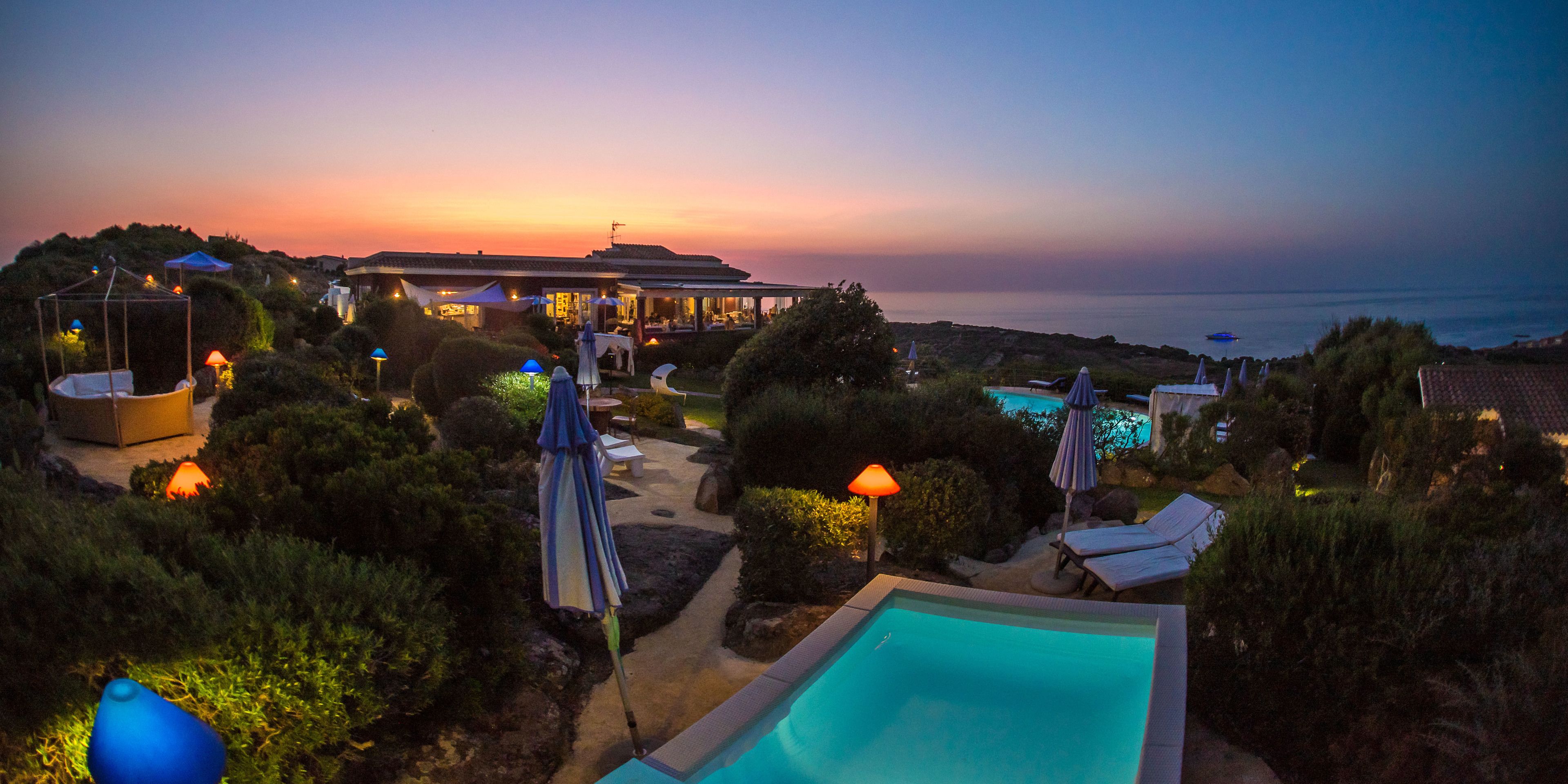 Un complexe hôtelier doté d’une piscine, de chaises longues, de parasols et offrant une vue sur le coucher de soleil.