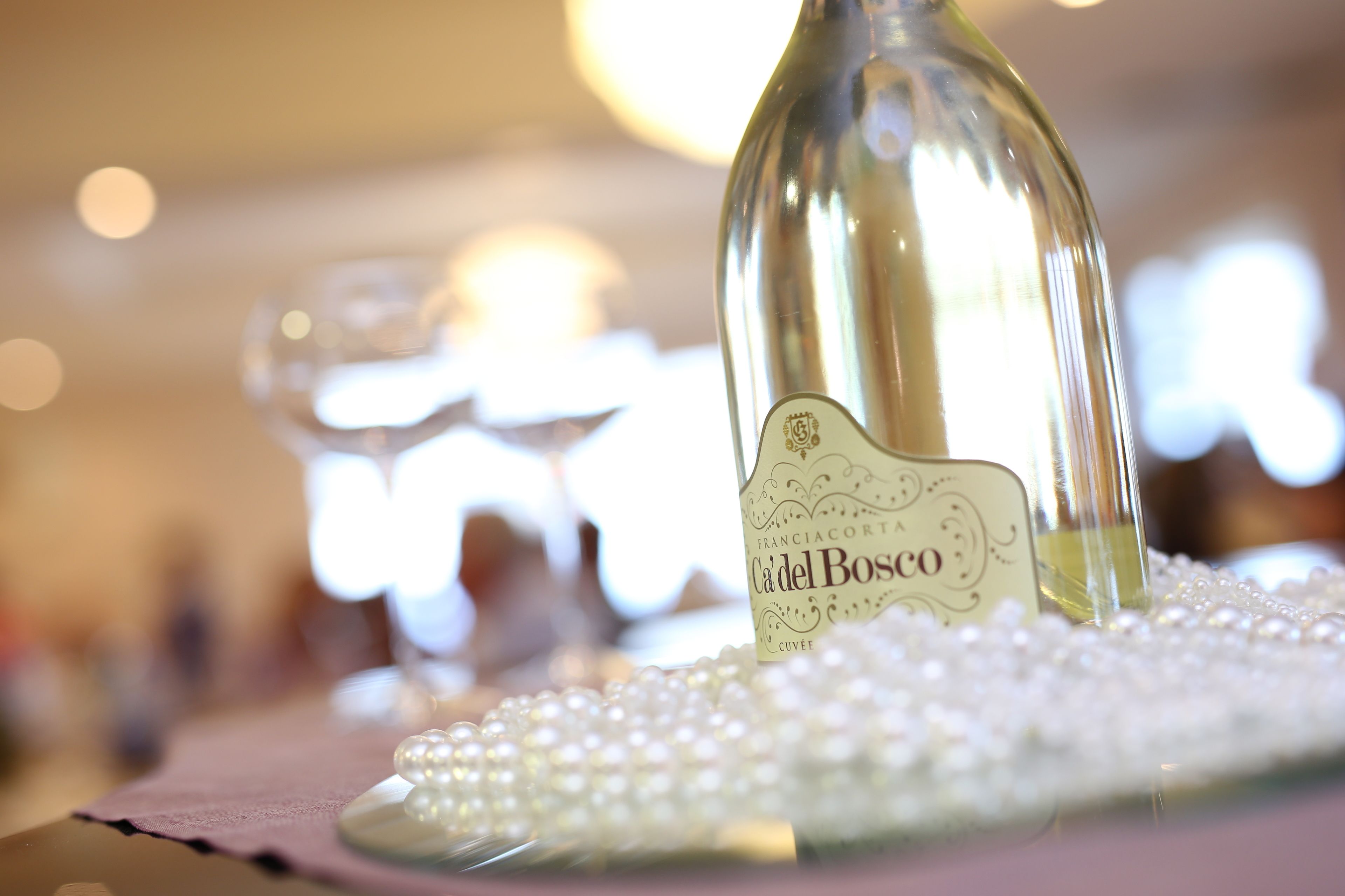 A bottle of Cầdel Bosco on a table with a pearl-like surface.