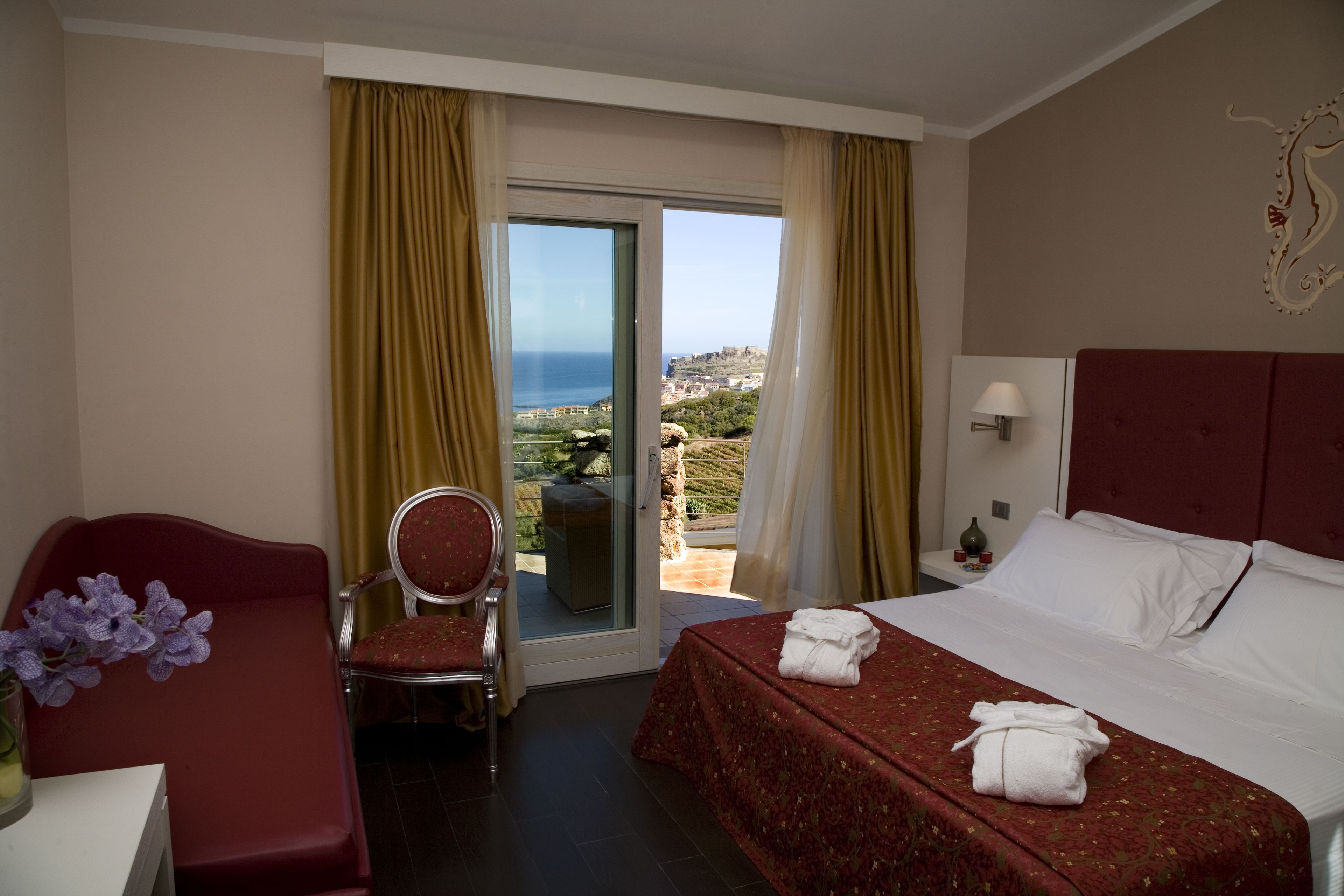 A hotel room with a bed, a desk, a chair, and a view of the sea.
