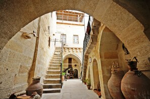 A narrow alleyway with stone walls, a staircase, and terracotta pots. - Cave Konak Hotel - Special Class (Ürgüp)
