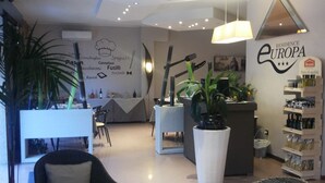 Een moderne hotellobby met een receptiebalie, een zithoek en een wand met decoraties met een culinair thema.