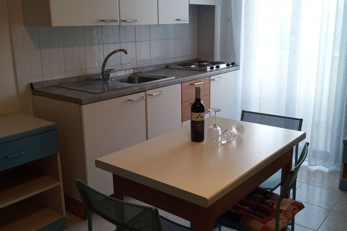 A compact kitchen with white cabinets, a sink, and a dining area with a table and chairs.