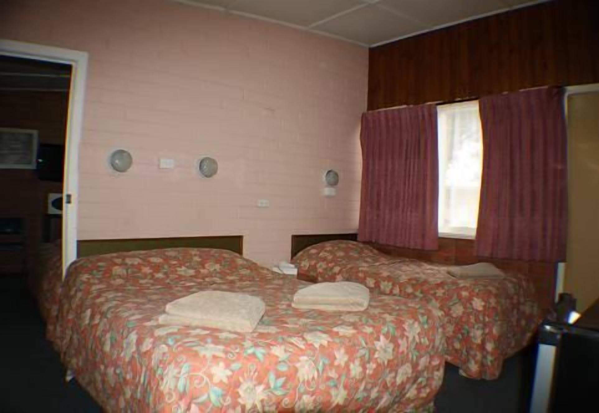 Una habitación doble con dos camas, una ventana con cortinas y una puerta.