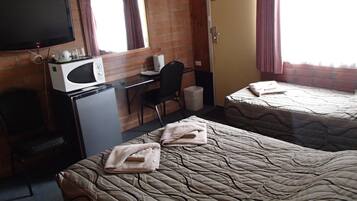 Ein Hotelzimmer mit zwei Betten, einem Schreibtisch, einem Fernseher und einer Mikrowelle.