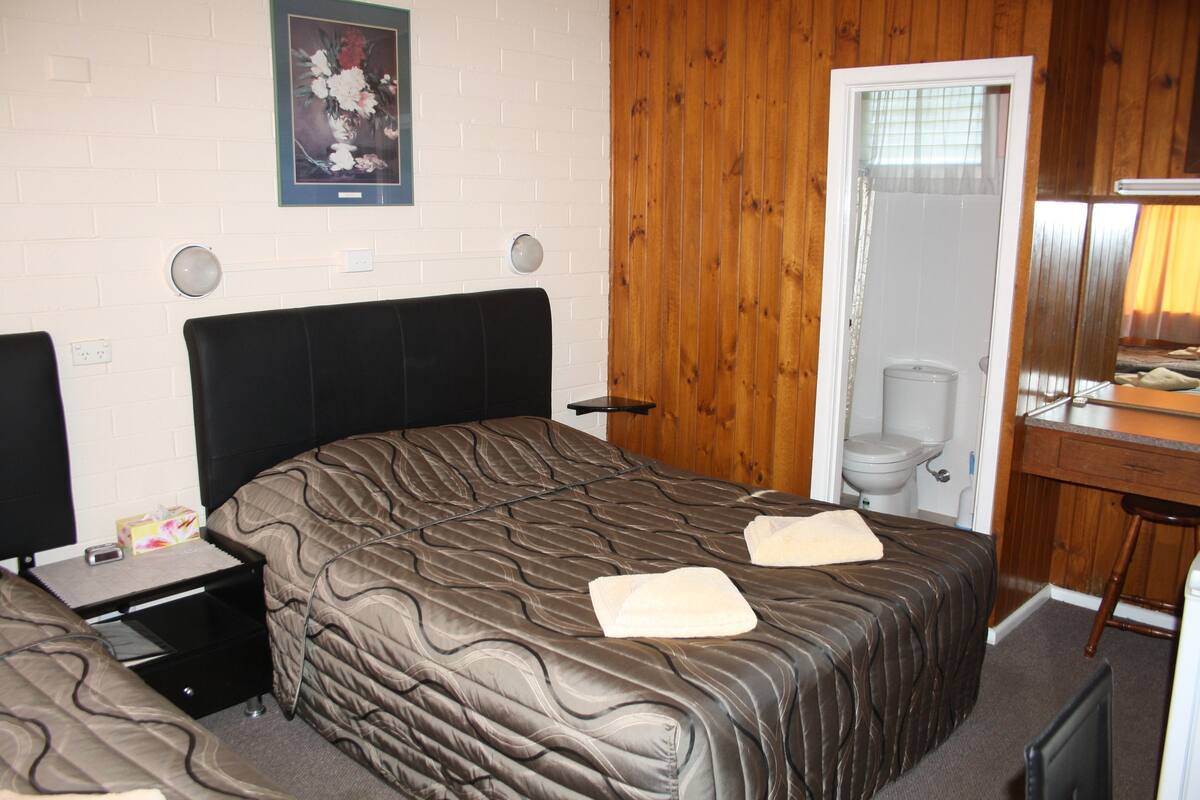 A bedroom with a bed, bedside table, and a wooden wall.