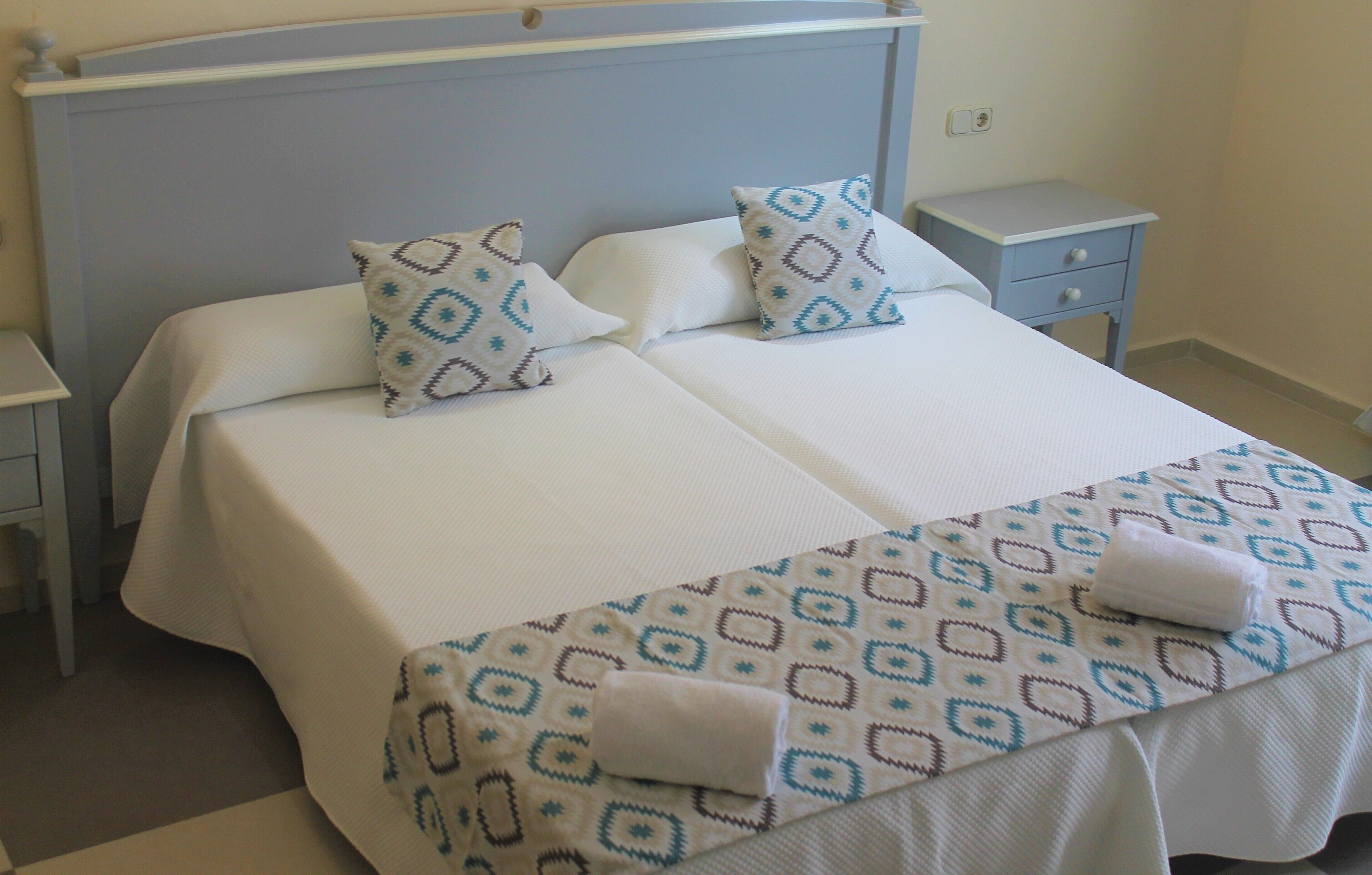 A double bed with two pillows, a bedside table, and a nightstand.