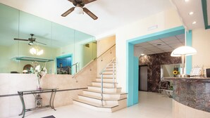 A hotel lobby with a reception desk, a staircase, a ceiling fan, and a seating area. - Hotel Playa Sol (Palma de Mallorca)