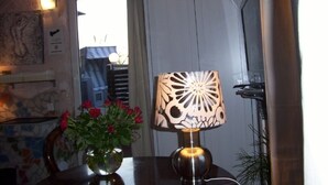 A table with a vase of red roses, a decorative lamp, and a view of a door and window. - Fritzi's Art Hotel (Filderstadt)