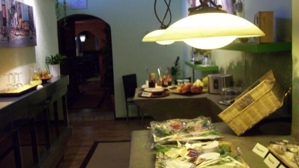 A restaurant with a table set for a meal, a hanging light fixture, and a view of the street outside. - Fritzi's Art Hotel (Filderstadt)
