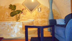 A room with a stone wall, a mirror, a vase, and a sofa. - Fritzi's Art Hotel (Filderstadt)