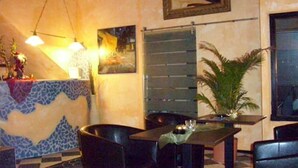 A restaurant interior with a checkered floor, a table with chairs, a potted plant, and a wall-mounted mirror. - Fritzi's Art Hotel (Filderstadt)