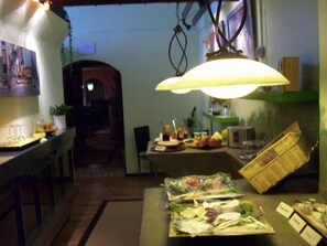 A restaurant interior with a dining table set for a meal, a hanging light fixture, and a view of the street outside. - Fritzi's Art Hotel (Filderstadt)