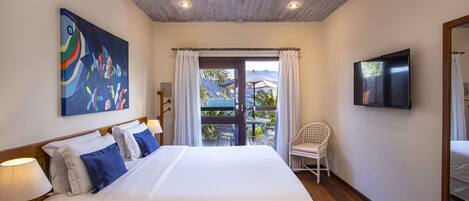 A bedroom with a large bed, a painting on the wall, a TV, and a view of the outdoors.