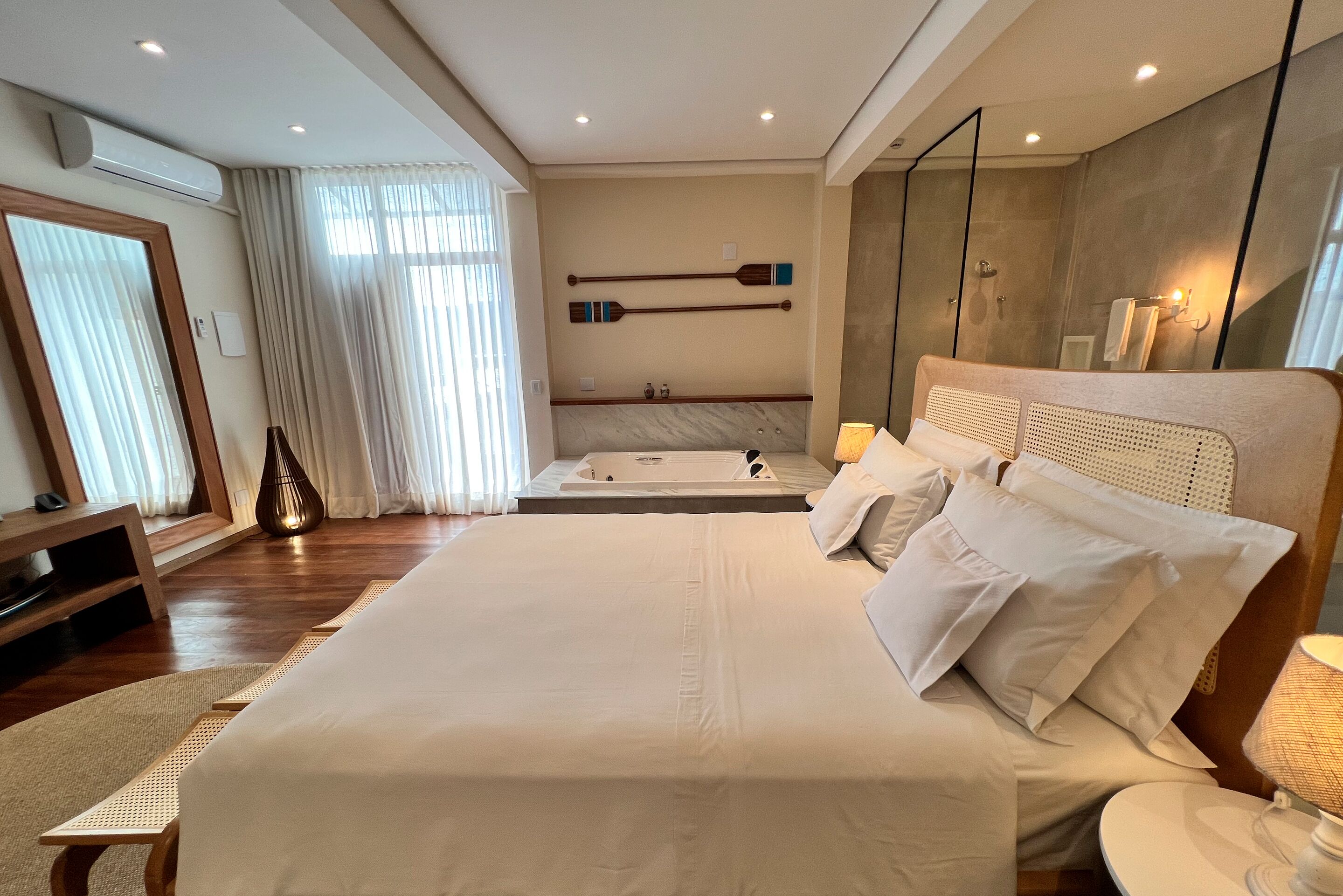 Un'ampia camera da letto con un grande letto, un'area salotto separata, una vasca da bagno e un ampio specchio.
