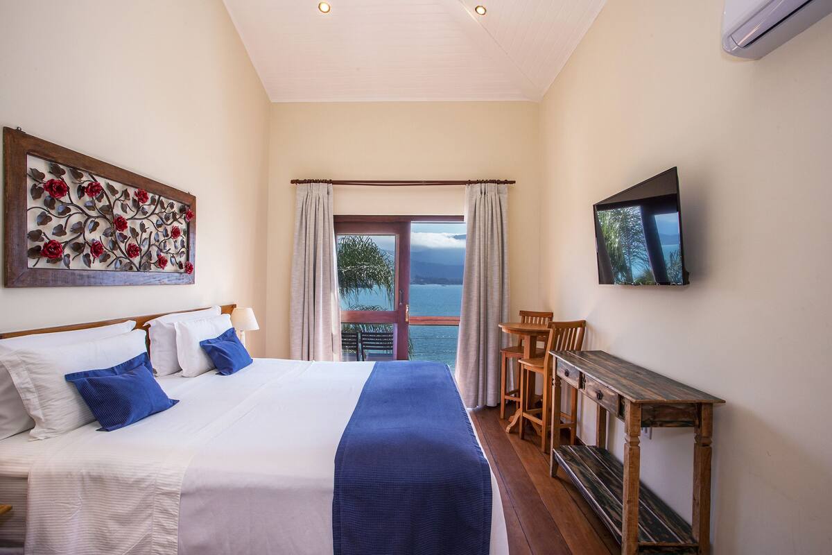 Een hotelkamer met een bed, een bureau, een stoel, een televisie en een raam met gordijnen.