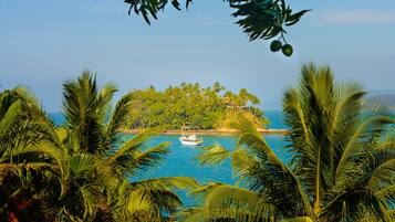 Una isla tropical con un bote en el agua, rodeada de palmeras y un cielo azul despejado.