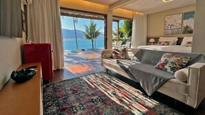 Een hotelkamer met een groot bed, een bank, een tafeltje en uitzicht op zee.