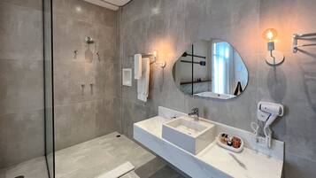 A modern bathroom with a glass shower enclosure, a large mirror, and a vanity with a sink and towel rack.