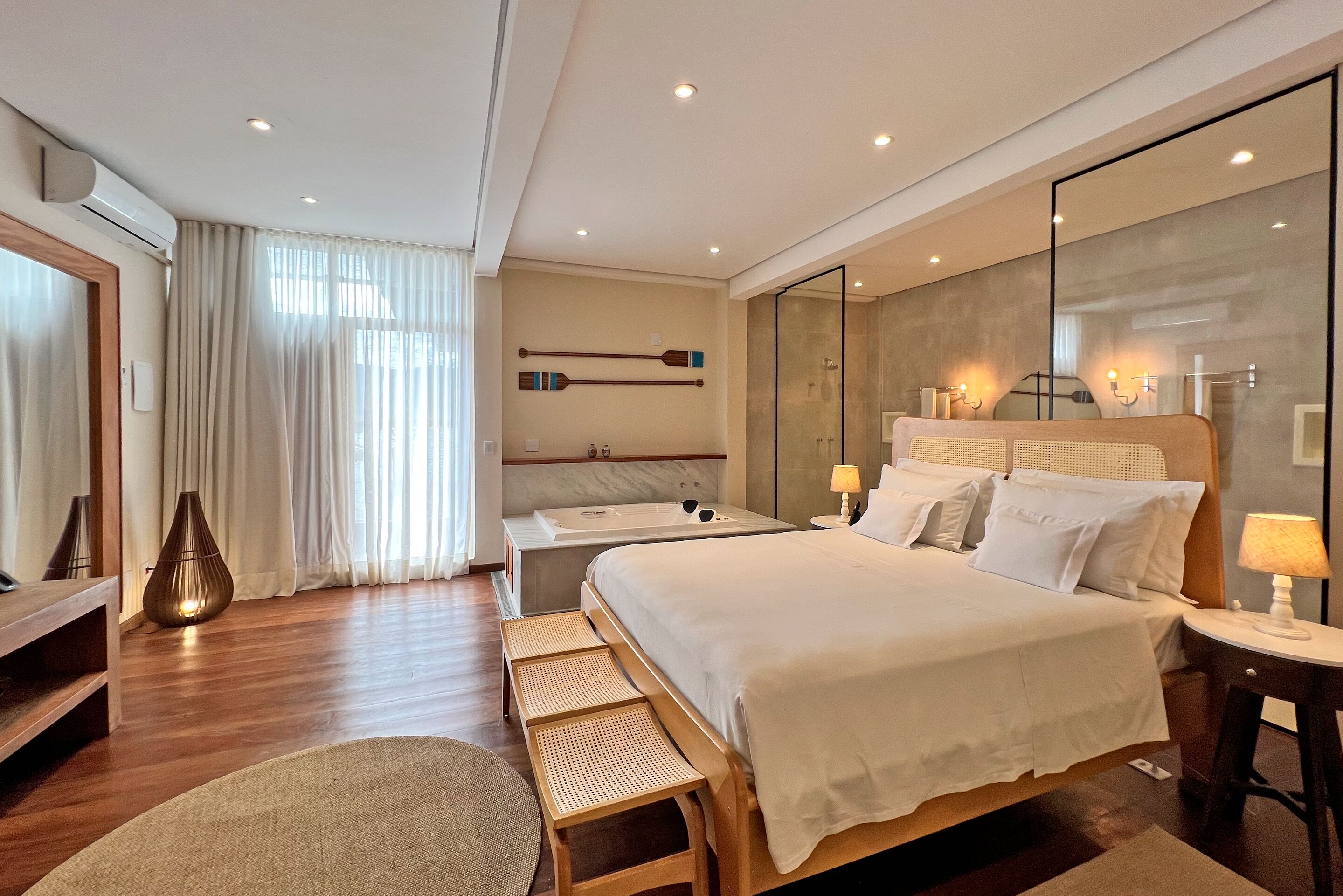 Habitació d'hotel moderna amb un llit gran, una taula de nit, un mirall i una zona de seients amb una banca.