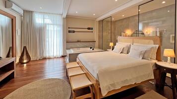 Habitació d'hotel moderna amb un llit gran, una taula de nit, un mirall i una zona de seients amb una banca.