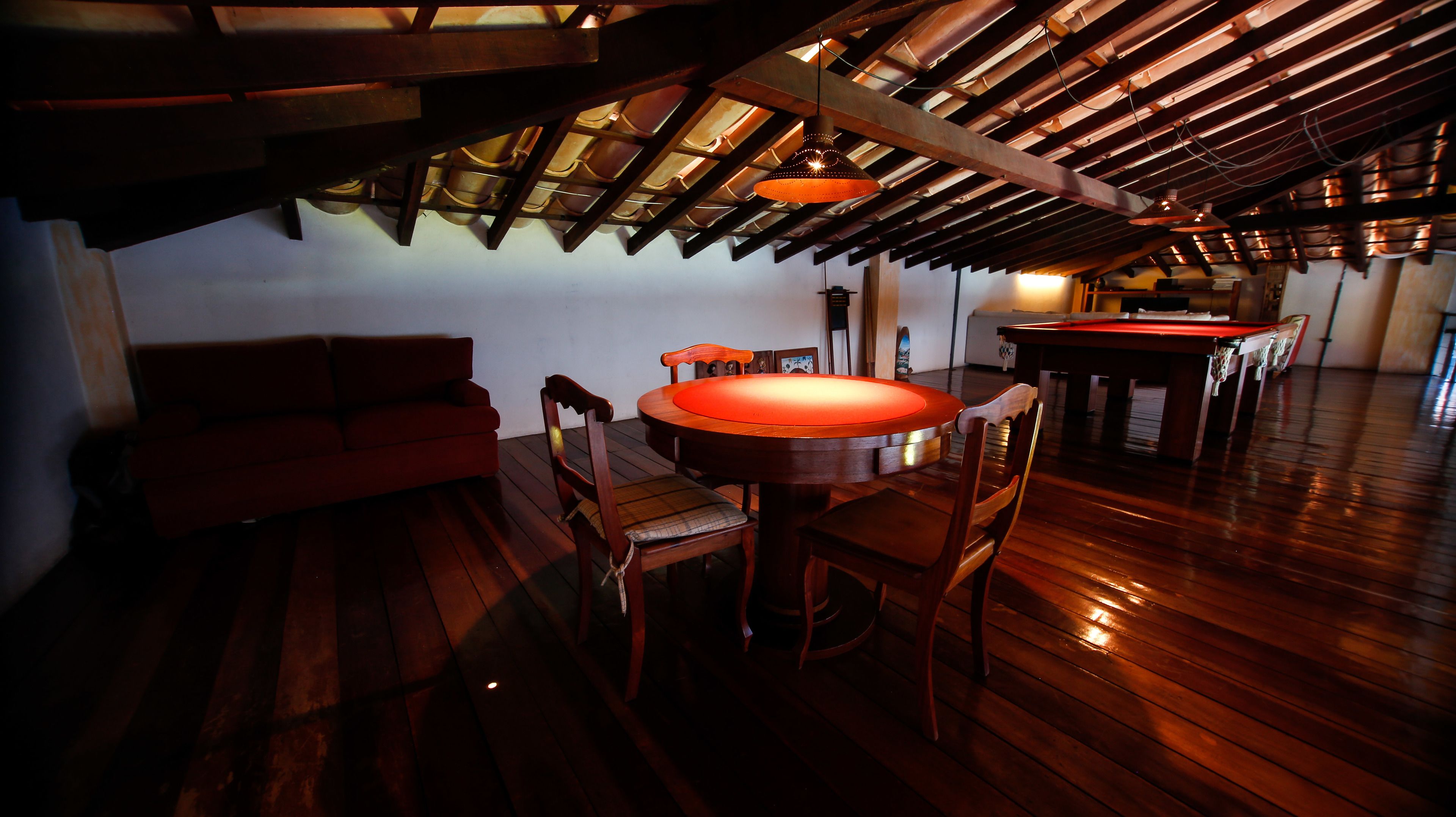 Una habitación acogedora con techo de madera, una mesa redonda de comedor y un sofá rojo.