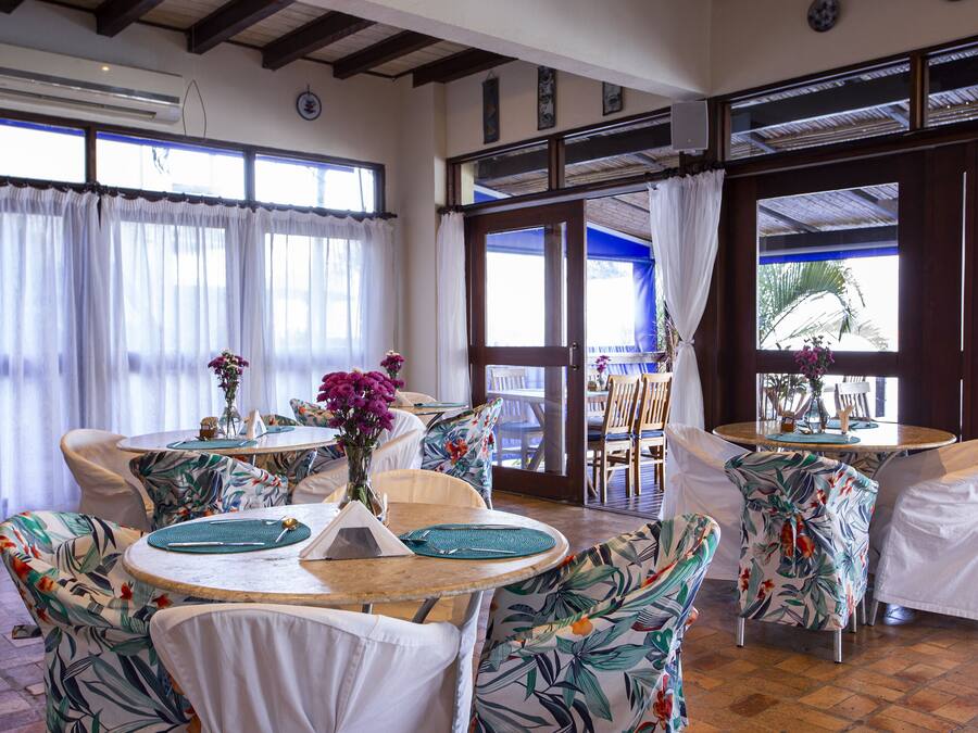 A dining area with round tables, chairs, and a tropical-themed decor.