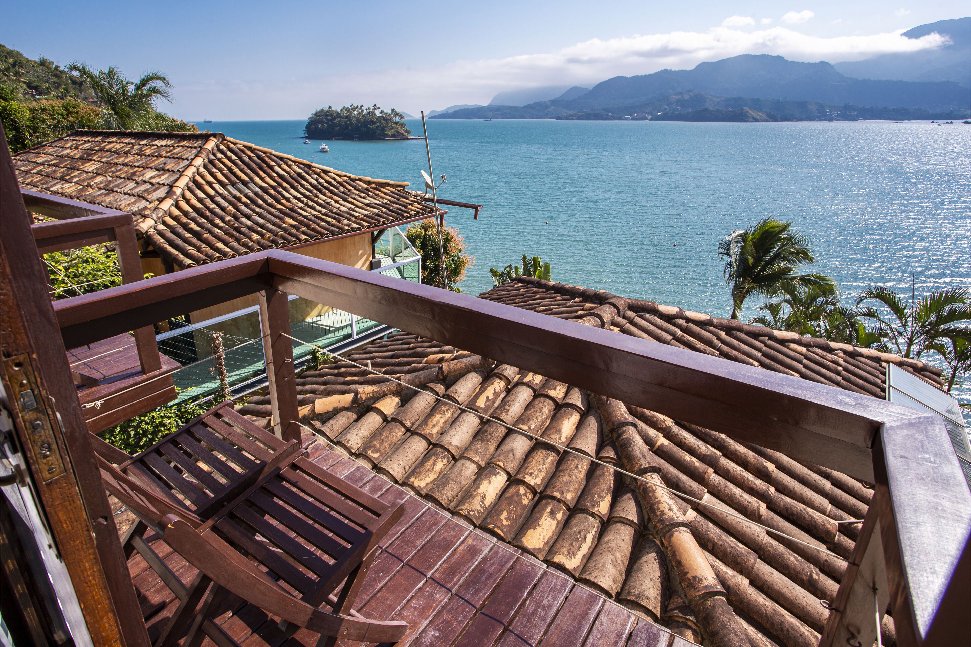 A wooden deck with a view of a calm sea and distant mountains.