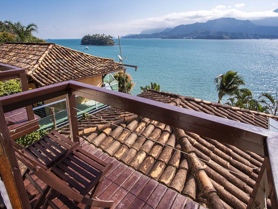 A wooden deck with a view of a calm sea and distant mountains.