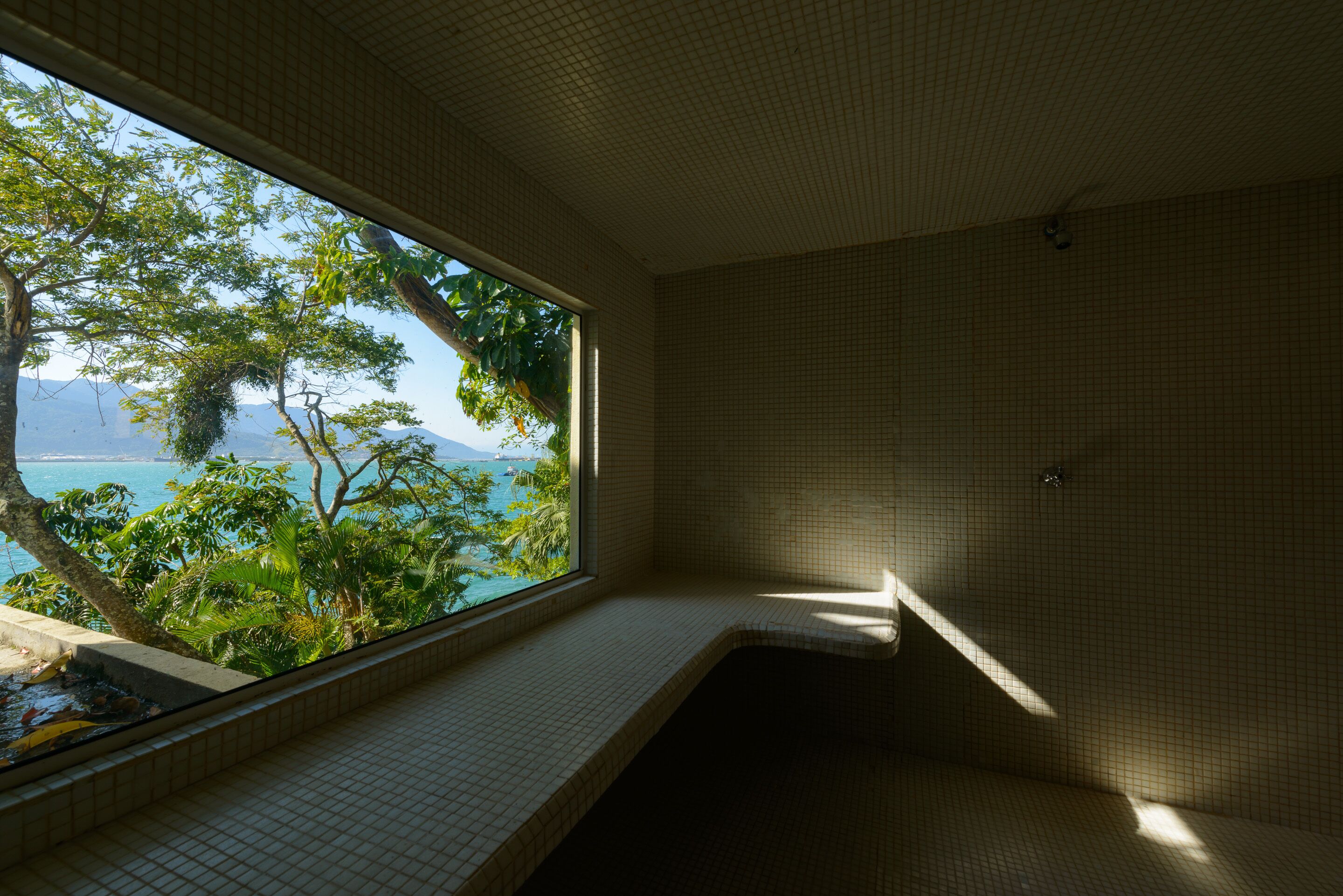 Un baño con vista a un paisaje tropical y una piscina.