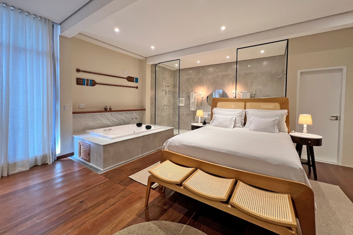 Een moderne hotelkamer met een groot bed, een aparte badkamer met bad en een grote spiegel.